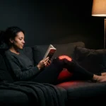 Red light therapy knee wrap worn while reading on the sofa